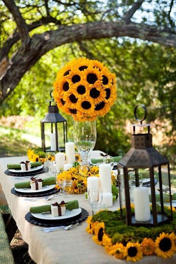 A garden table decorated with sunflowers, candles and lanterns for a special occasion